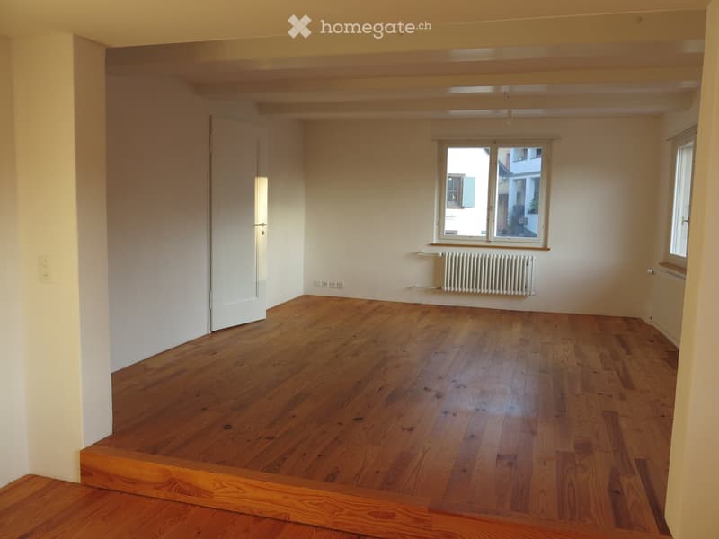 Unfurnished Room. Empty room with wooden flooring, white walls, and a large window with a view of the street.