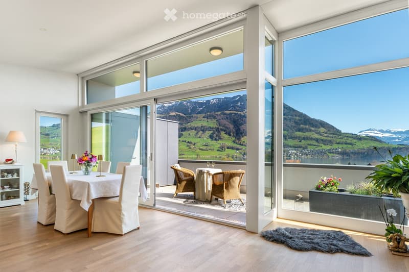 Furnished Room. Bright dining area with large windows offering scenic mountain views, featuring a dining table with chairs, a flower vase, and a sideboard with table lamps.