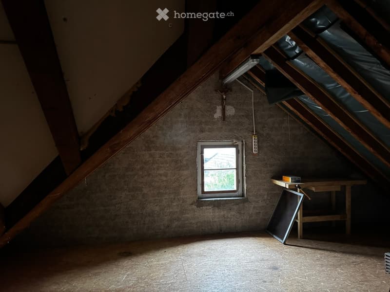 Unfurnished Room. Empty attic space with wooden beams, a small window, and a simple wooden table with a few items on it.