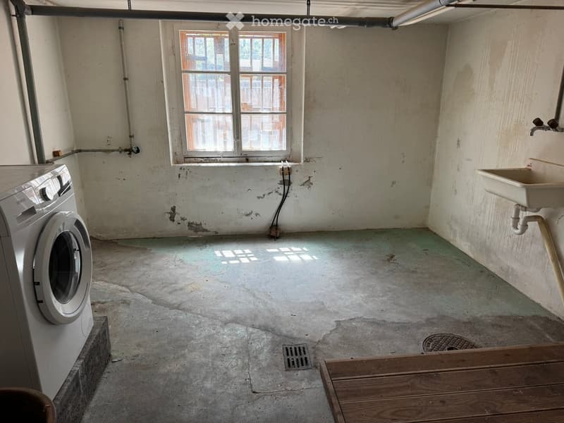 Unfurnished Room. Empty room with concrete floor, exposed pipes, a window, a washing machine, and a sink.