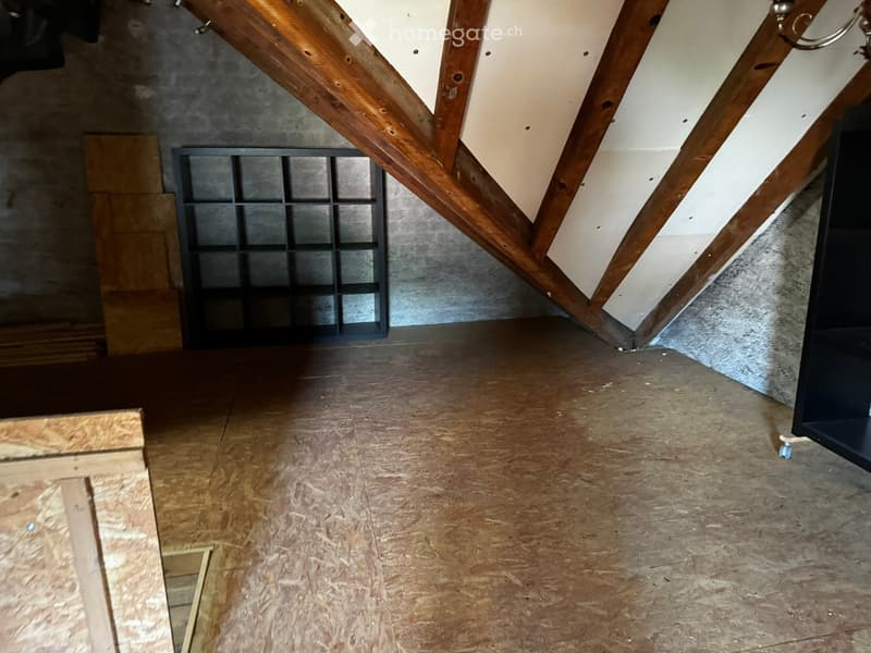 Unfurnished Room. Empty attic space with wooden beams, exposed wooden floor, and a metal-framed window. No furniture or equipment present.