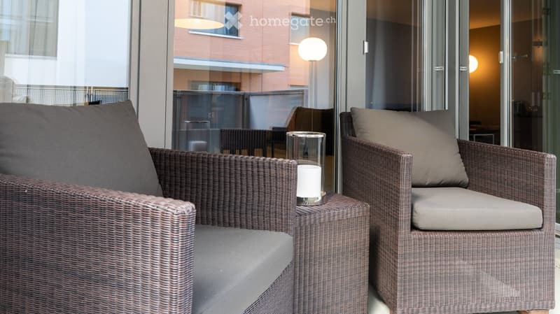 Balcony / Terrace. Balcony with two wicker armchairs, a small side table with a candle, and a view of the building exterior.