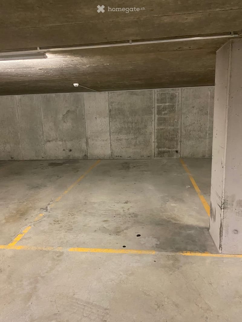 Building. Empty underground parking space with concrete walls, floor, and yellow parking lines.
