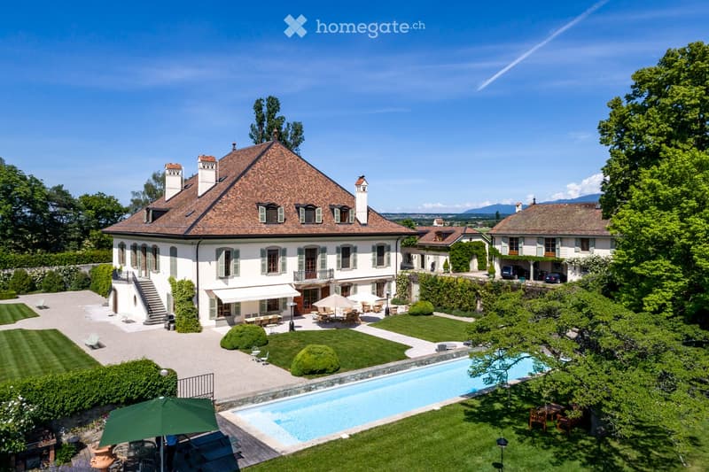 House. Large, elegant house with a classic design, surrounded by a well-maintained garden, featuring a swimming pool, outdoor seating areas, and a garage.