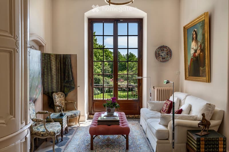 Other. {"visible_features": [],    "type": "Room",    "description": "white walls, beige flooring, white couch, center table with flower vase, wooden bench, radiator, framed painting on the wall, two armchairs, side table, and a lamp",    "localized_de