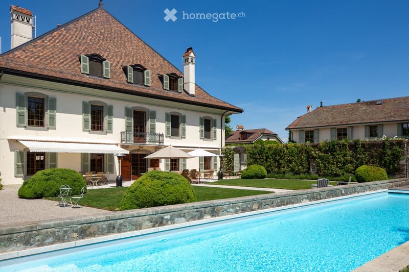 House. Traditional villa, swimming pool, garden, white walls, brown roof, several windows, patio with umbrellas and tables