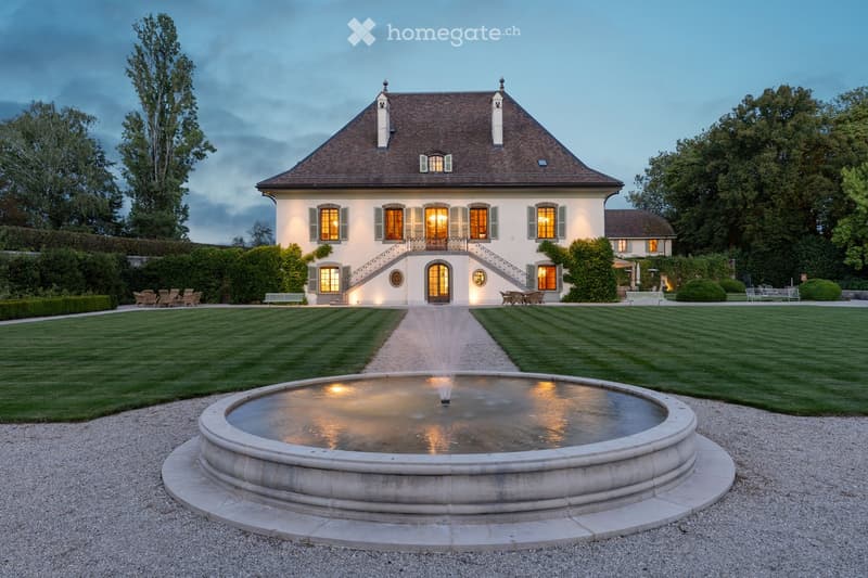 House. large house, brown roof, white exterior, landscaped garden, fountain, illuminated at night