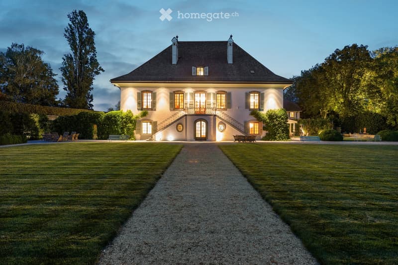 House. spacious house, lit up at night, wide driveway, large lawn, terrace