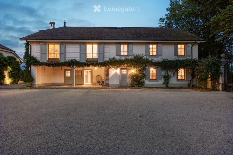 House. large house with brown roof, white walls, several windows, porch, gravel driveway, plants, bicycle in front