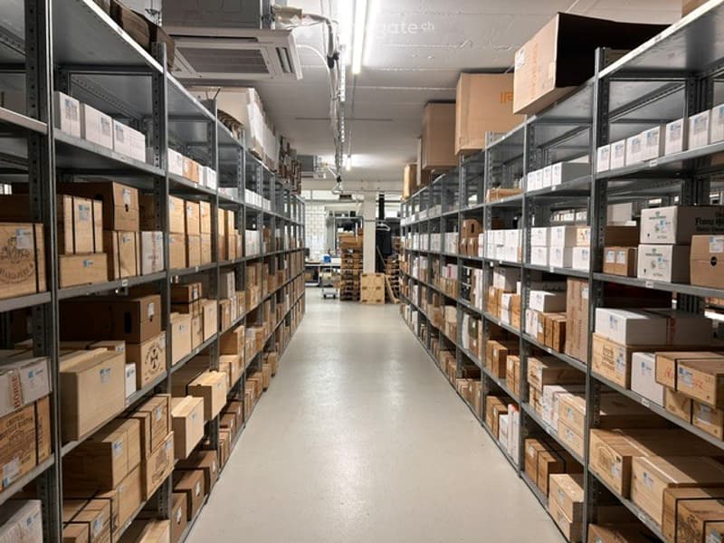 Other. A storage area with metal shelving units filled with cardboard boxes, organized in rows, and fluorescent lighting overhead.