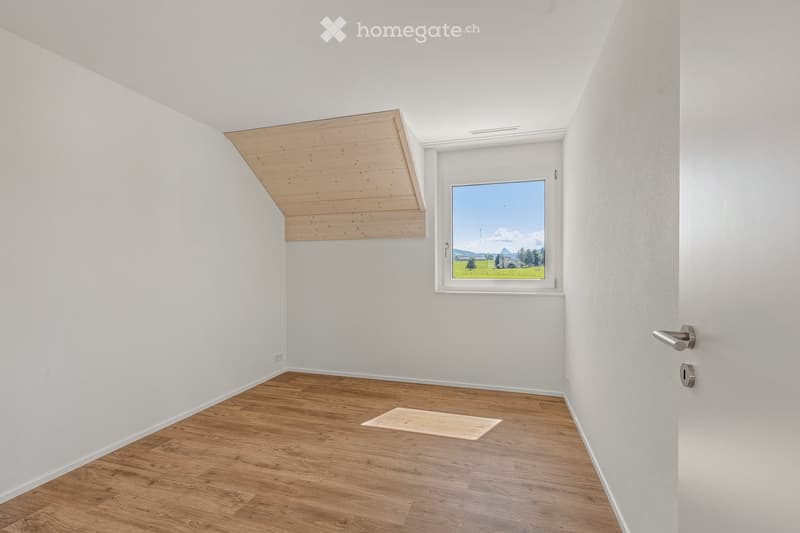 Unfurnished Room. Empty room with wooden flooring, white walls, and a large window offering a scenic view of a field and mountains.