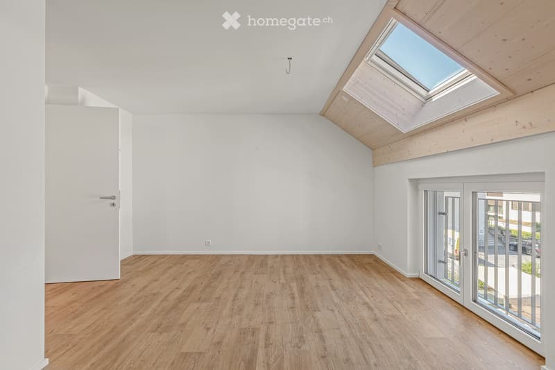 Unfurnished Room. Empty room with wooden flooring, white walls, and large windows, including a skylight and a sliding glass door leading outside.