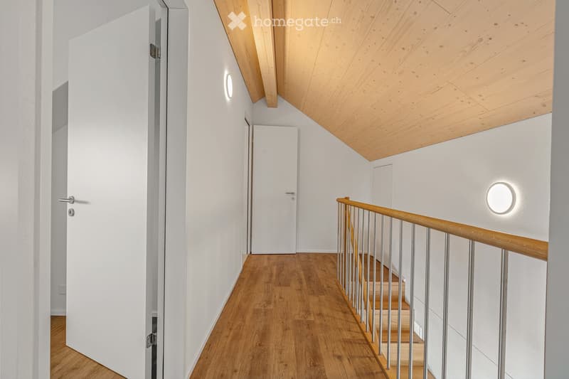 Corridor / Hallway. Modern hallway with wooden flooring, white walls, and a staircase leading upwards. Features include built-in lighting, a sleek wooden handrail, and a minimalist design.
