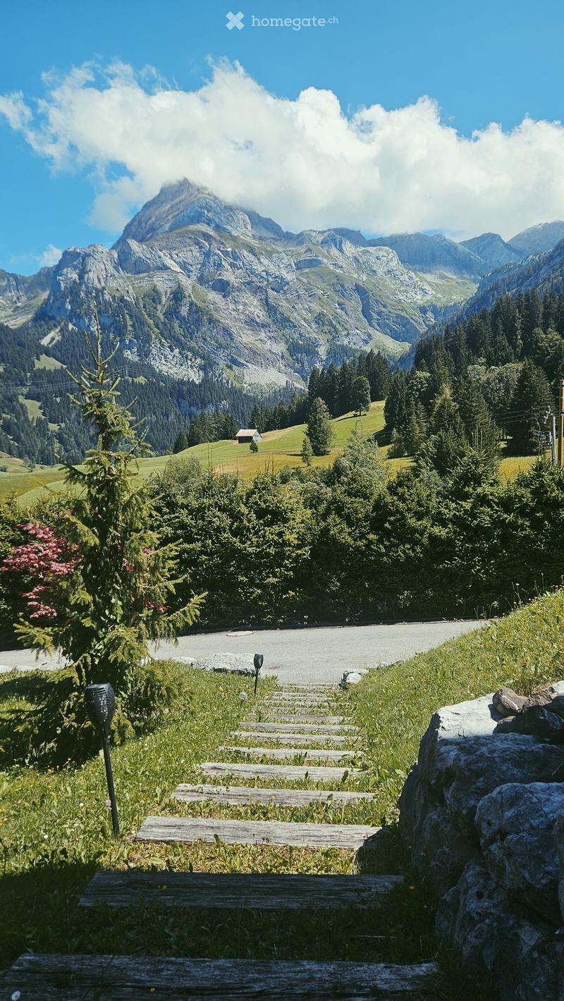 Wooden pathway leading up to a stone wall with a view of a mountain valley