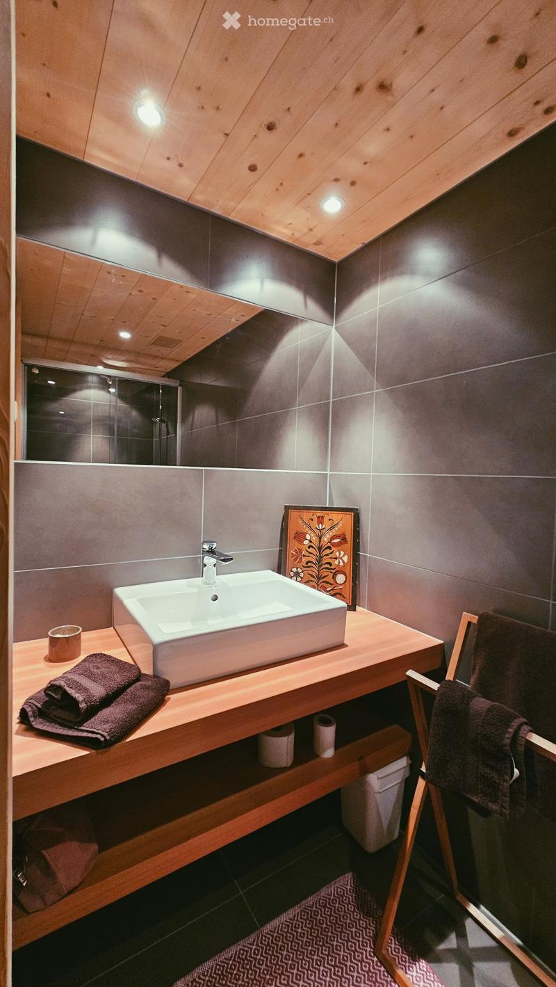 wooden shelves, white sink, towel rack, towels, tiles, glass shower enclosure