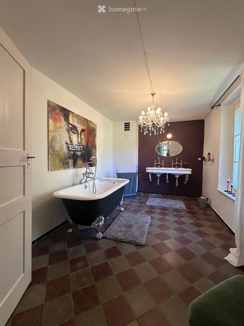 Bathroom. Bathroom with a large, black and white clawfoot bathtub, double sink, chandelier, and a large picture frame on the wall.