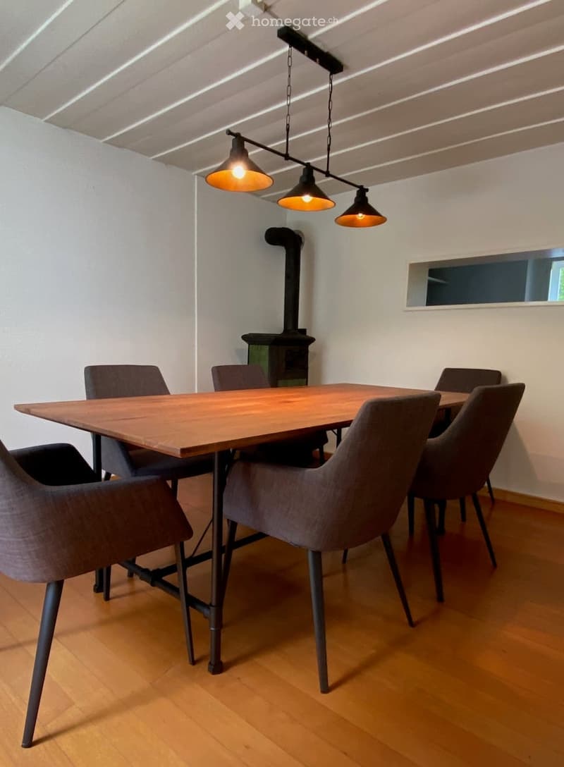 Furnished Room. Dining room with a wooden table, six chairs, and a fireplace in the background.