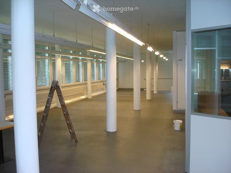 Unfurnished Room. Empty room with concrete floor, white walls, large windows with shutters, white columns, and industrial lighting. Ladder and bucket visible.