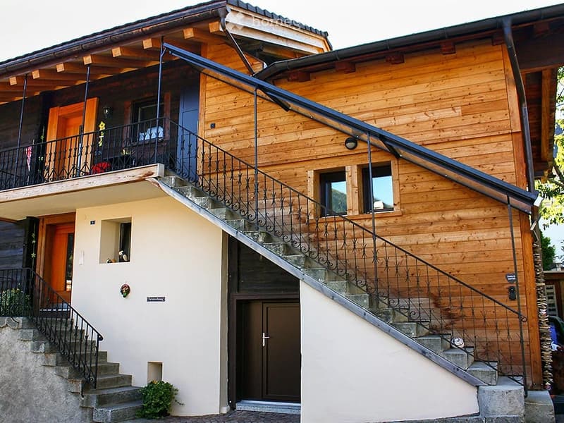 Wooden exterior with stairs and balcony, 3 story building, brown doors