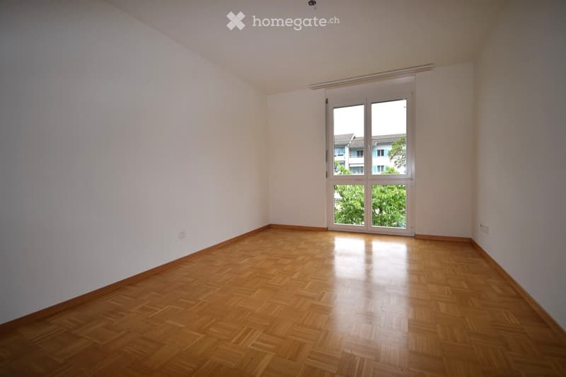 Unfurnished Room. Empty room with wooden flooring and white walls, featuring a large window with a view of the outside.