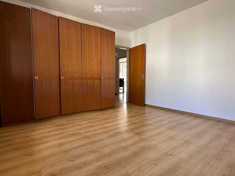 Unfurnished Room. Empty room with light wooden flooring, white walls, and a large set of wooden built-in wardrobes.