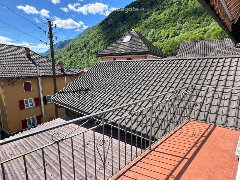 Balcony / Terrace. Terrace with red-tiled floor and metal railing overlooking neighboring rooftops and a mountainous landscape.