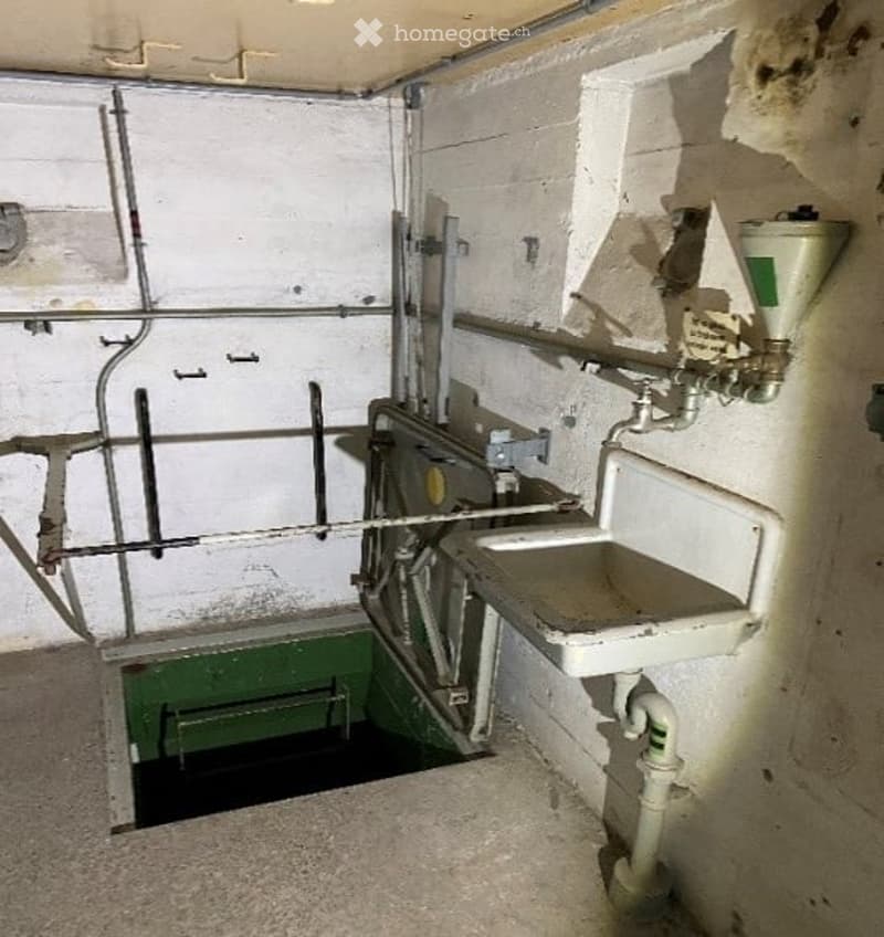 Unfurnished Room. An empty utility or service room with a sink, metal framework, and a green compartment, likely used for maintenance or storage.