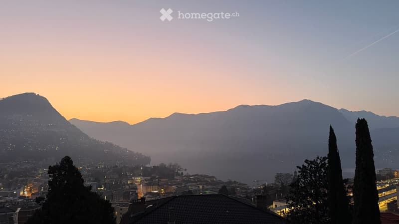 Cityscape with mountains, buildings, and a sunset view