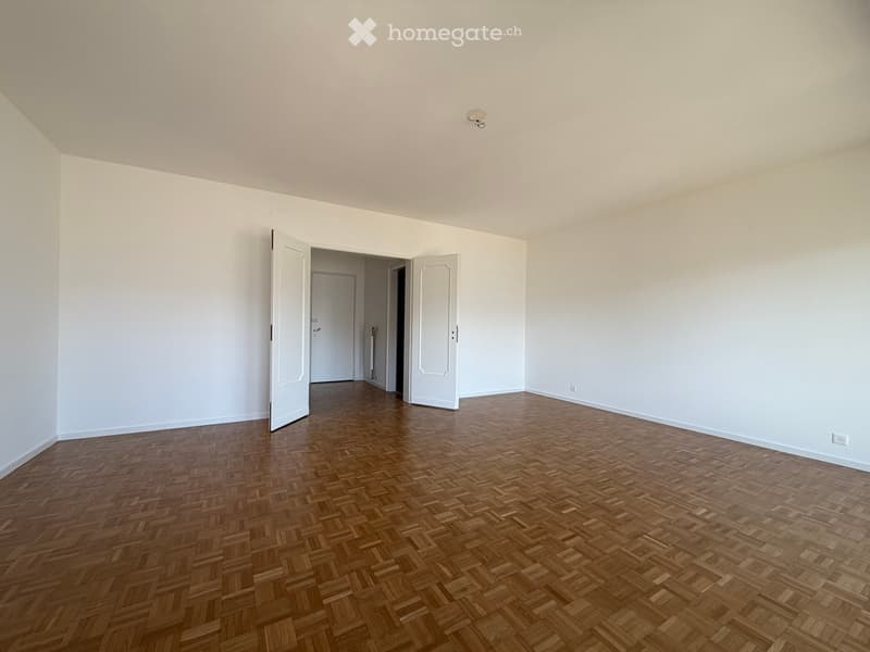 empty room, wooden parquet floor, white walls, two open doors, ceiling light