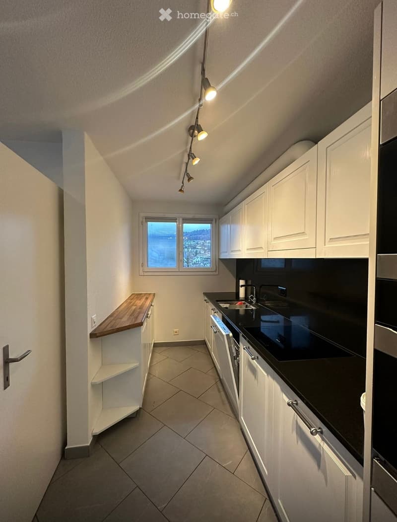 white kitchen with a window, wooden counter, black counters, white cabinets, built-in dishwasher, electrical outlets, sink, faucet, stainless steel appliances