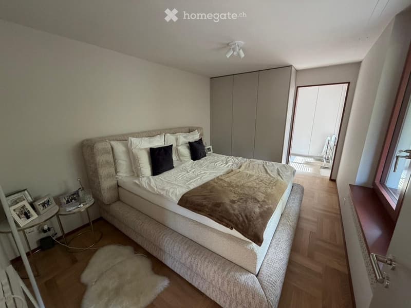 Bedroom. Modern bedroom with a large bed, nightstand, mirror, wardrobe, and a small table with picture frames.