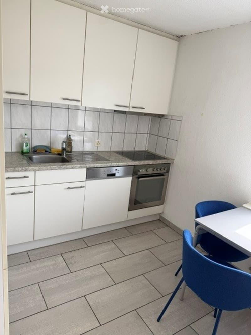 Kitchen. Modern kitchen with white cabinets, stainless steel appliances, and a small dining area with blue chairs.