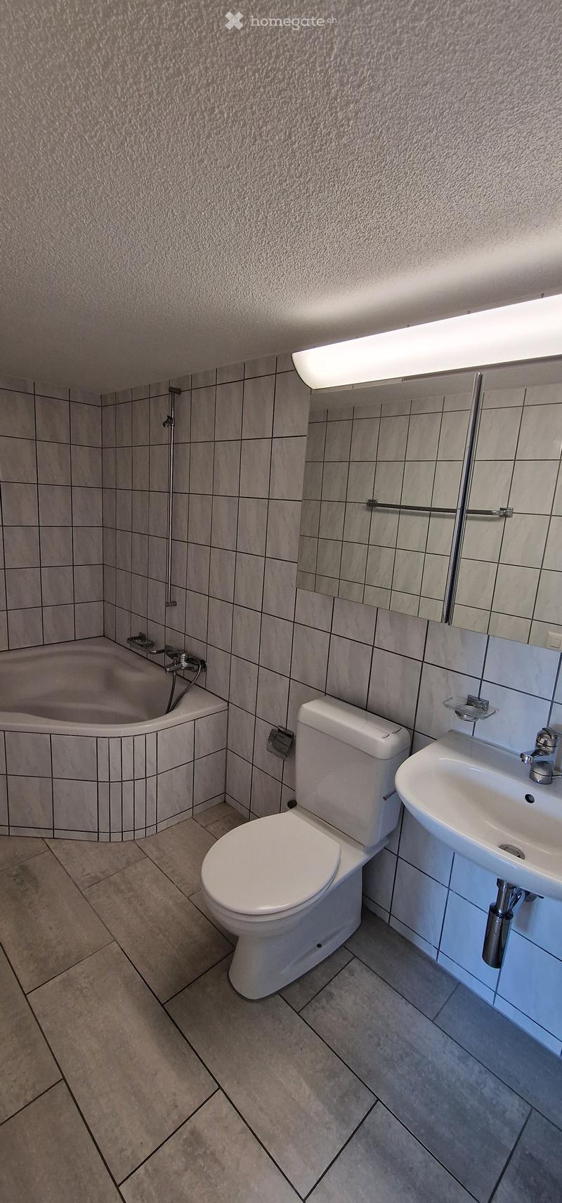 Bathroom. Modern bathroom with tiled walls and floor, featuring a bathtub, toilet, sink, and mirror.