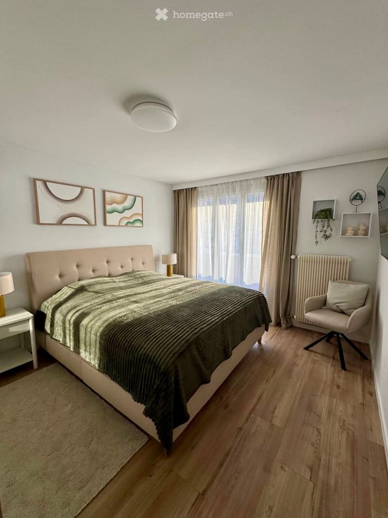 Bedroom with bed, nightstands, lamps, rug, radiator, chair, and paintings on the wall