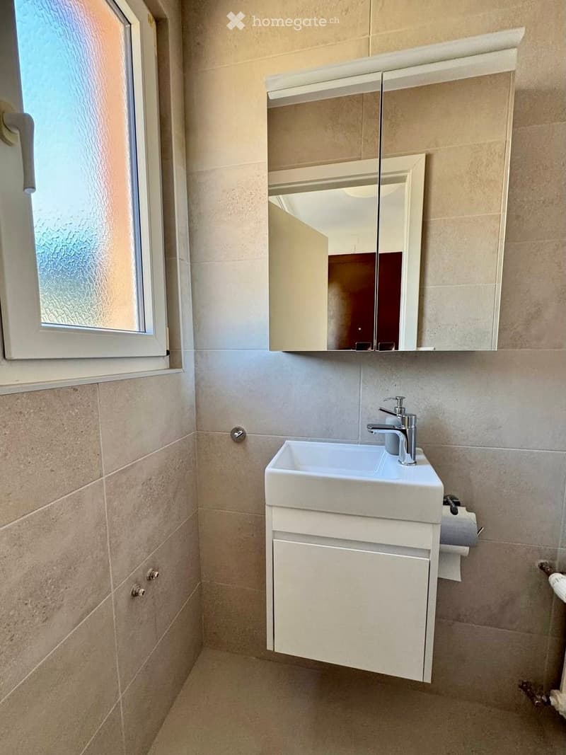 Bathroom with white sink, mirror, and tiled walls