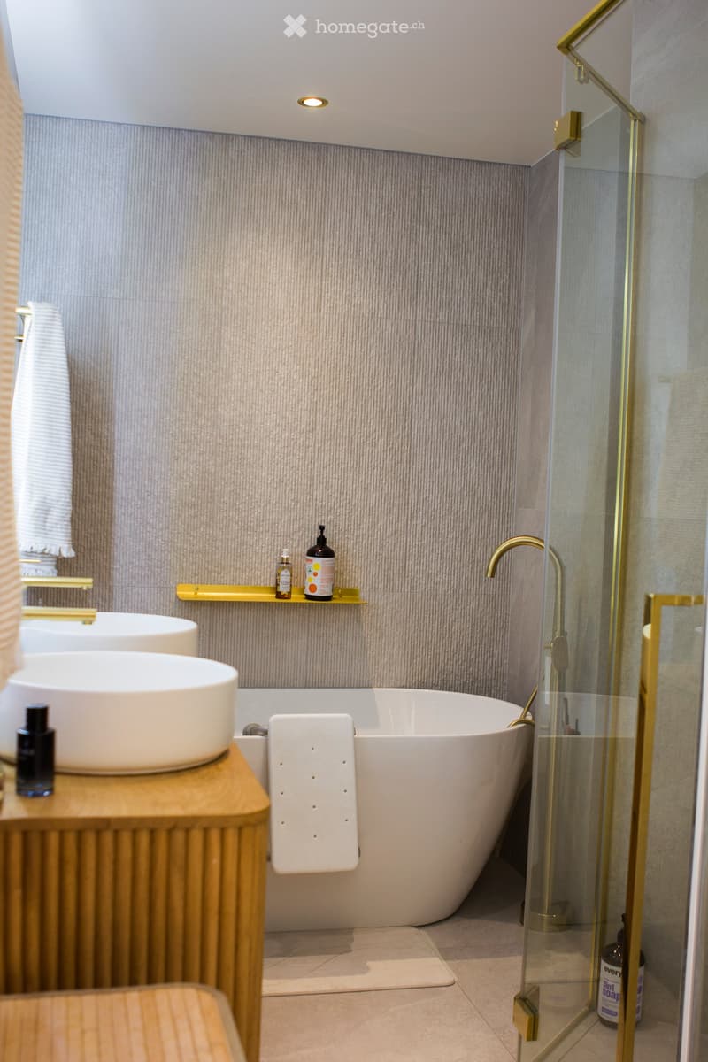 Bathroom. Modern bathroom with a freestanding bathtub, double sink vanity, glass shower enclosure, and gold fixtures.