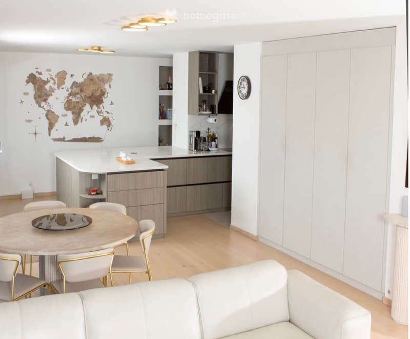Furnished Room. Modern open-plan living and dining area with a white leather sofa, round dining table with four chairs, kitchen island, and fitted kitchen cabinets.