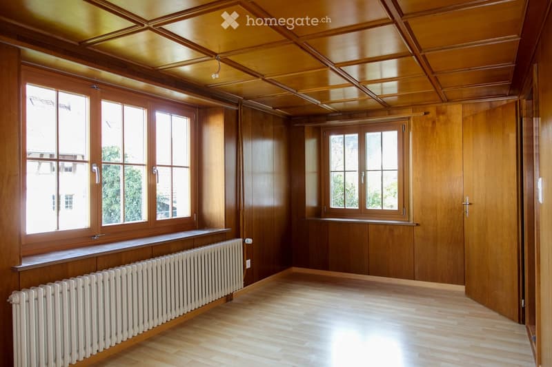 Unfurnished Room. Empty room with wooden walls, wooden ceiling, large windows, and radiators.