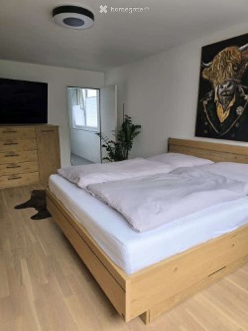 Bedroom. Bright bedroom with a wooden bed, white bedding, a nightstand, a plant, and a mirror on the wall.