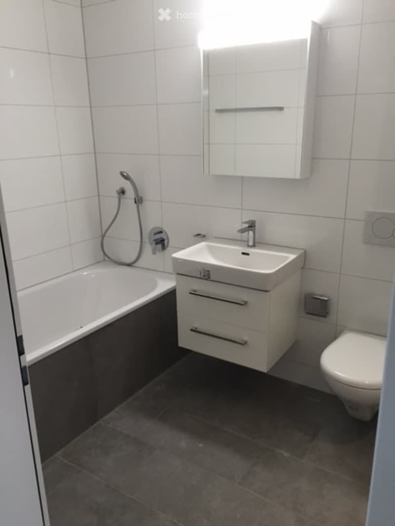 Bathroom: white tiles, bathtub, sink, cabinet, toilet, overhead shower
