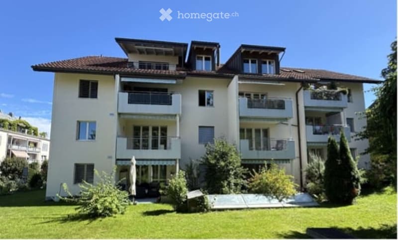 Building. Multi-story residential building with balconies, large windows, and a well-maintained lawn in front.