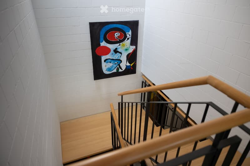 Corridor / Hallway. Staircase with wooden steps, metal railing, and a colorful abstract painting on the wall.