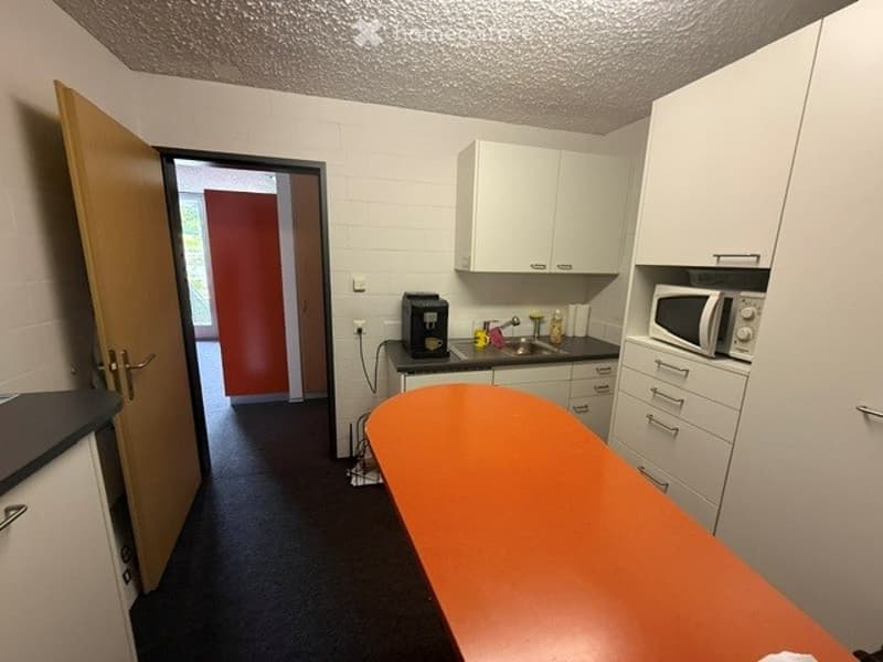 Kitchen. Modern kitchen with white cabinets, a microwave, coffee maker, sink, and a bright orange countertop.