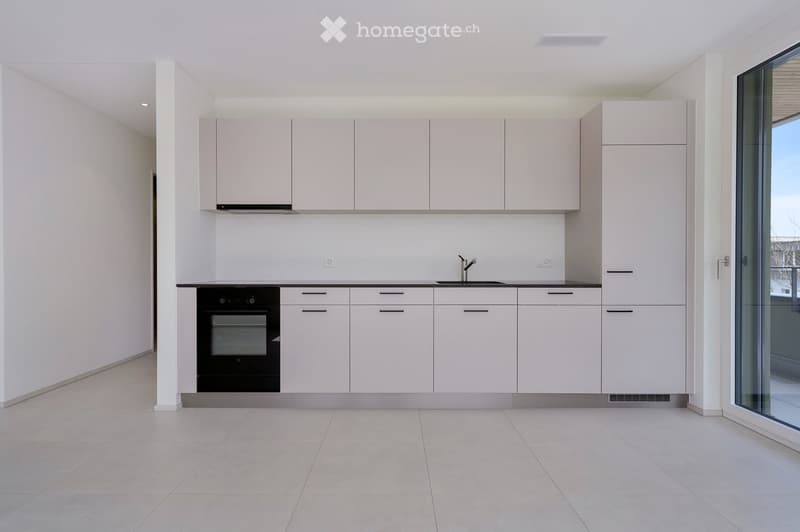 Kitchen. Modern kitchen with white cabinets, black countertop, built-in oven, and a sink with a faucet.