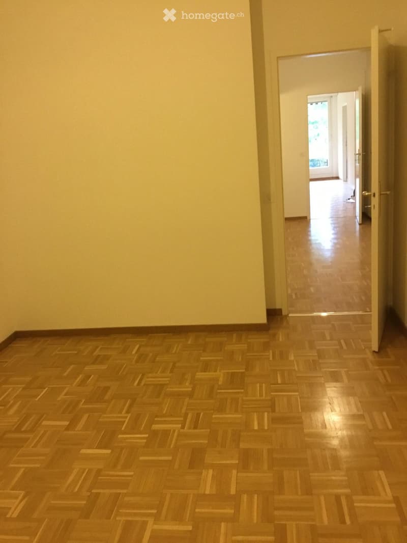 Unfurnished Room. Empty hallway with wooden flooring and light-colored walls, featuring an open doorway leading to another room.