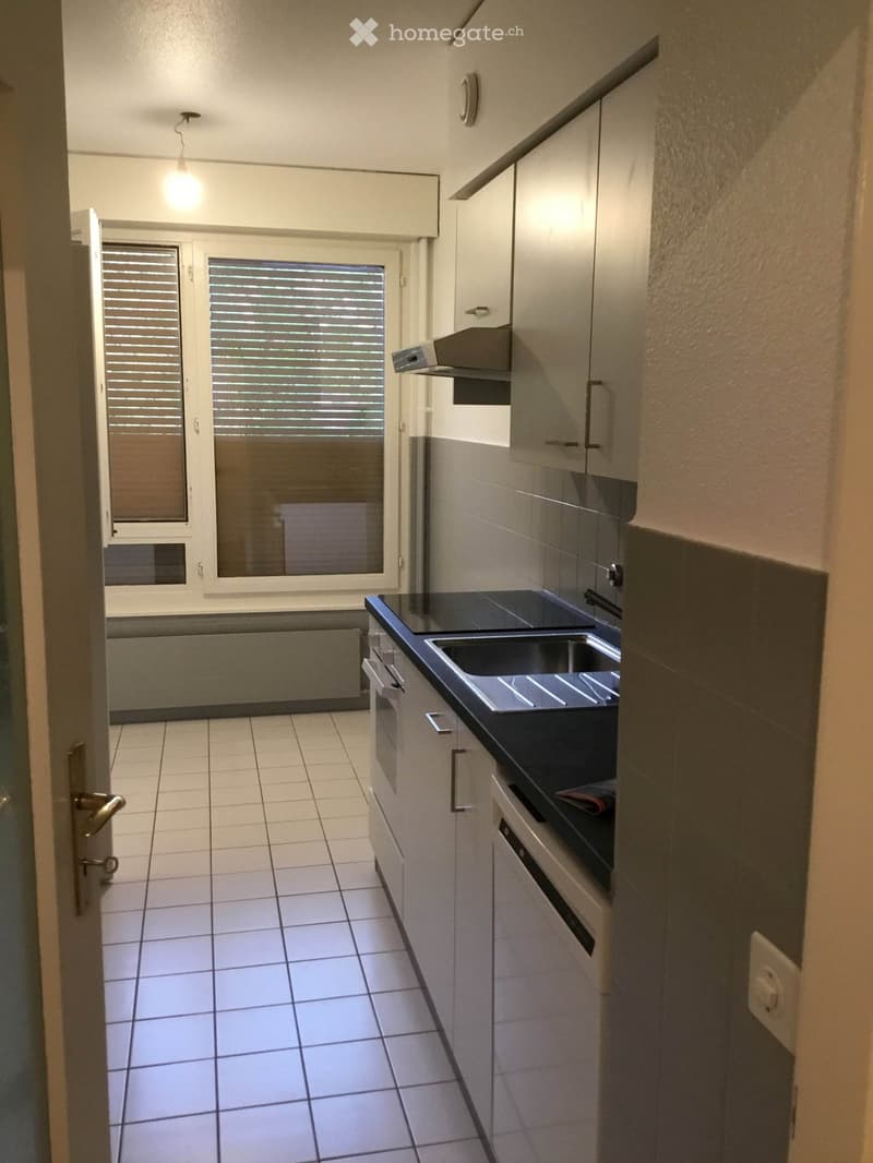 Kitchen. Modern kitchen with white tiled floor, grey cabinets, black countertop, and stainless steel sink.