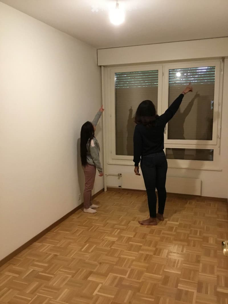Unfurnished Room. Empty room with wooden flooring, white walls, and a large window with blinds. No furniture or equipment is present.