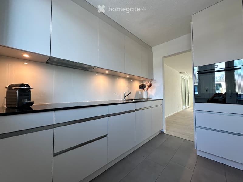 Kitchen. Modern kitchen with white cabinets, black countertop, coffee machine, and a vase on the counter.