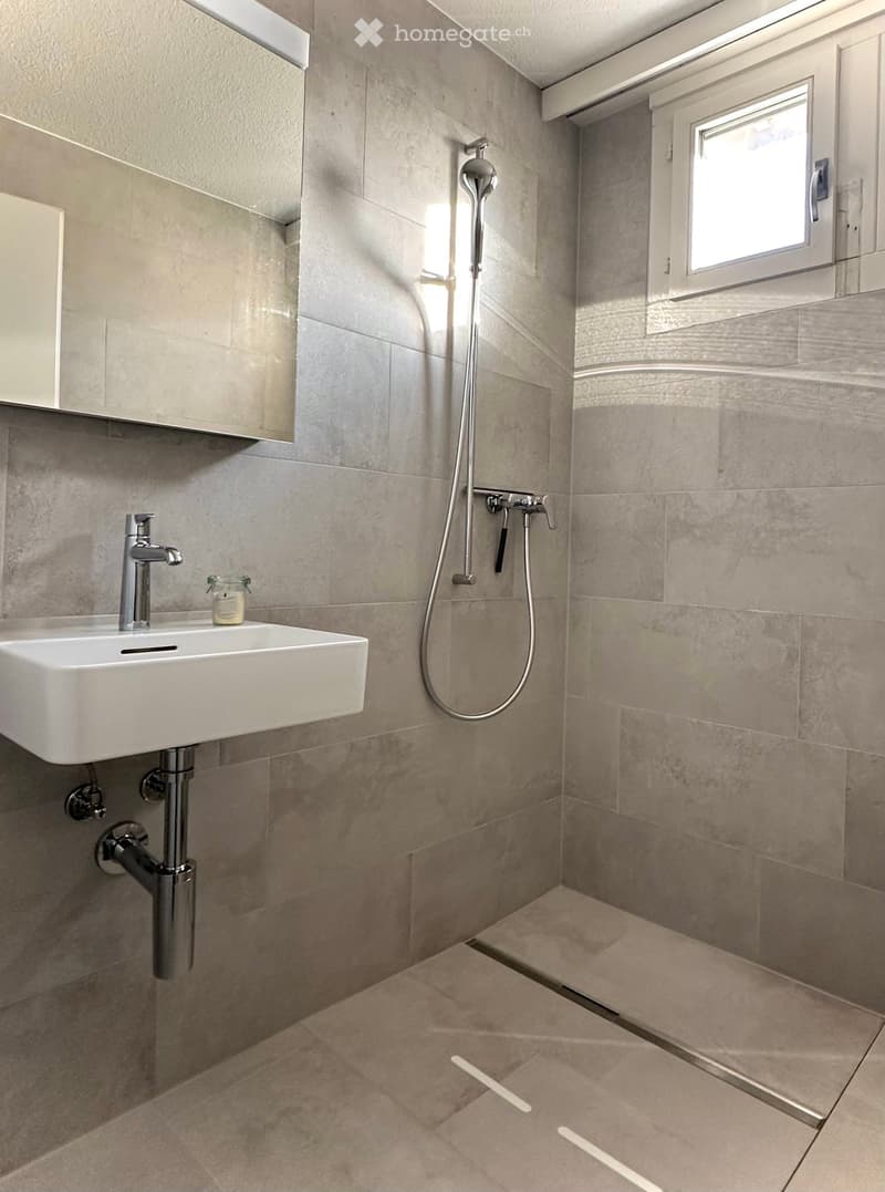 Bathroom. Modern bathroom with a white sink, chrome faucet, shower head, and a small window. The walls and floor are tiled in a light beige color.