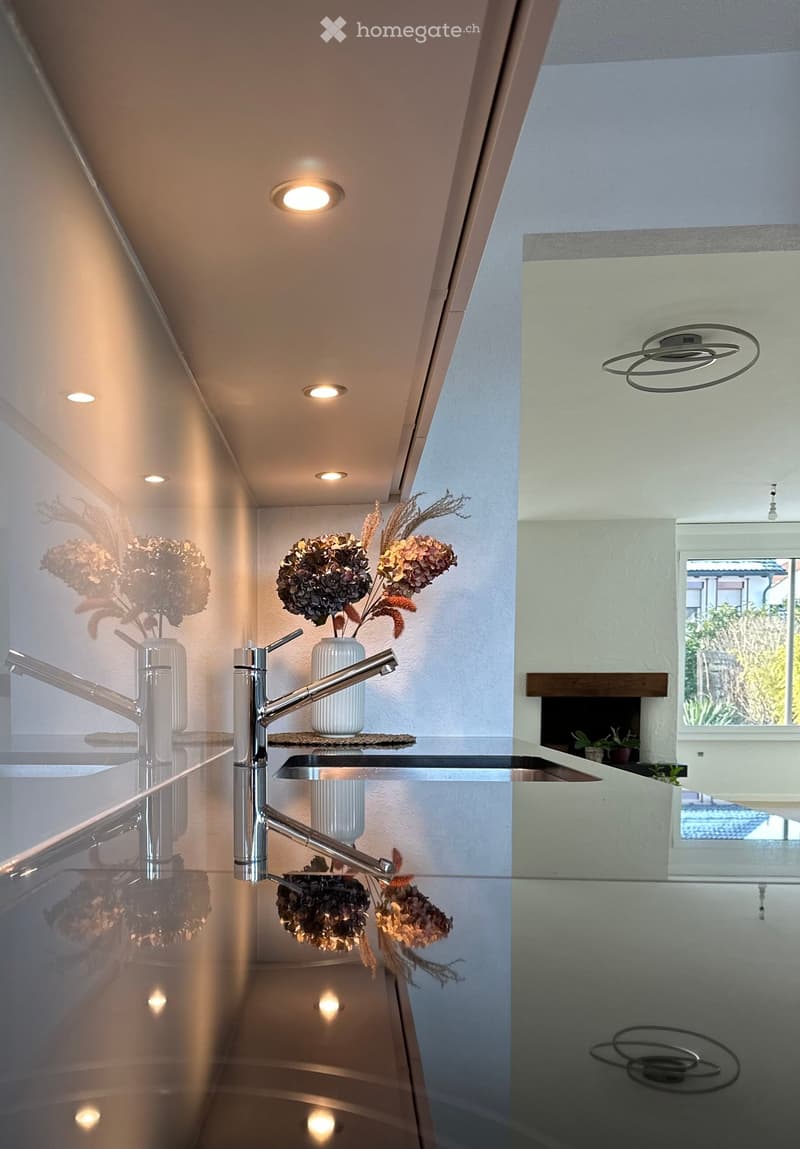 Corridor / Hallway. Modern hallway with sleek glass railing, recessed ceiling lights, and decorative vases with dried flowers on a glass shelf.